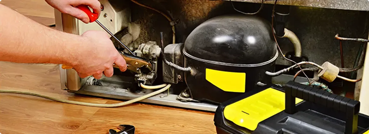 Refrigerator repair technician fixing the compressor and wiring in Meraux, LA
