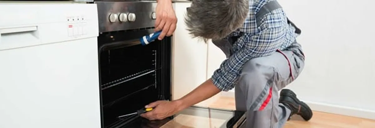 Oven repair technician inspecting and servicing an electric oven in New Orleans, LA