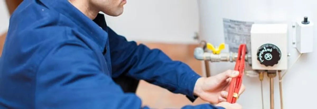 Water heater repair technician adjusting the temperature control and gas valve in New Orleans, LA